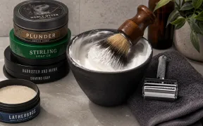 Assorted wet shaving soap pucks and tubs from various brands arranged on a flat surface