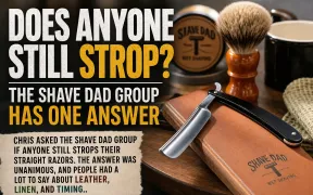 Leather strop hanging alongside a straight razor on a wooden surface, the standard setup for maintaining a razor's edge between honing sessions