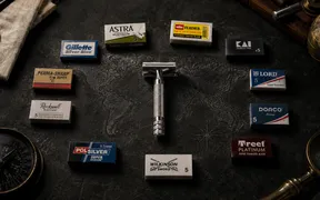 A vintage DE safety razor centered on a world map surrounded by blade packs from Astra, Feather, Kai, Gillette Silver Blue, Lord, Dorco, Perma-Sharp, Polsilver, Rockwell, Treet, and Wilkinson Sword