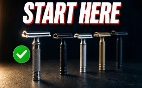A neat row of five beginner-friendly double-edge safety razors standing upright on a dark slate counter under warm side-light, a chrome three-piece razor in sharp focus in front with a small green check badge, headline START HERE in white block letters with a red drop shadow across the top