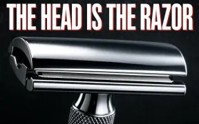 A dramatic macro photograph of a chrome double-edge safety razor head on dark slate, the domed top cap, exposed blade edge and smooth safety bar clearly stacked, knurled handle below, headline THE HEAD IS THE RAZOR in white block letters with a red drop shadow across the top