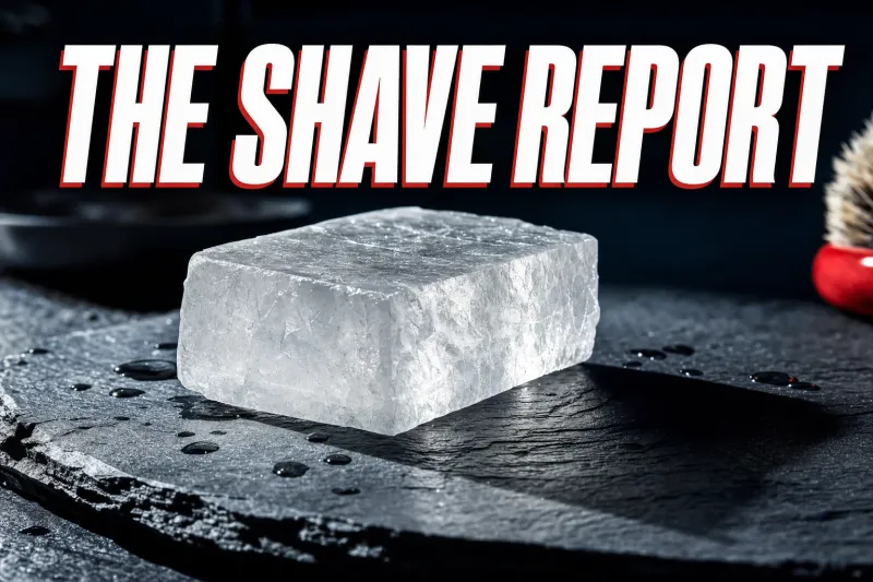A cinematic close-up of a translucent white crystalline alum block on a dark slate counter, catching hard side light with subtle internal facets and a few water droplets around it, headline THE SHAVE REPORT in white block letters with a red drop shadow across the top