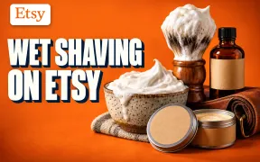 Wet Shaving on Etsy key art with the Etsy logo: a stoneware lather bowl, a lathered wooden-handled brush, artisan soap tins, an aftershave bottle and a leather strop on a bold orange background