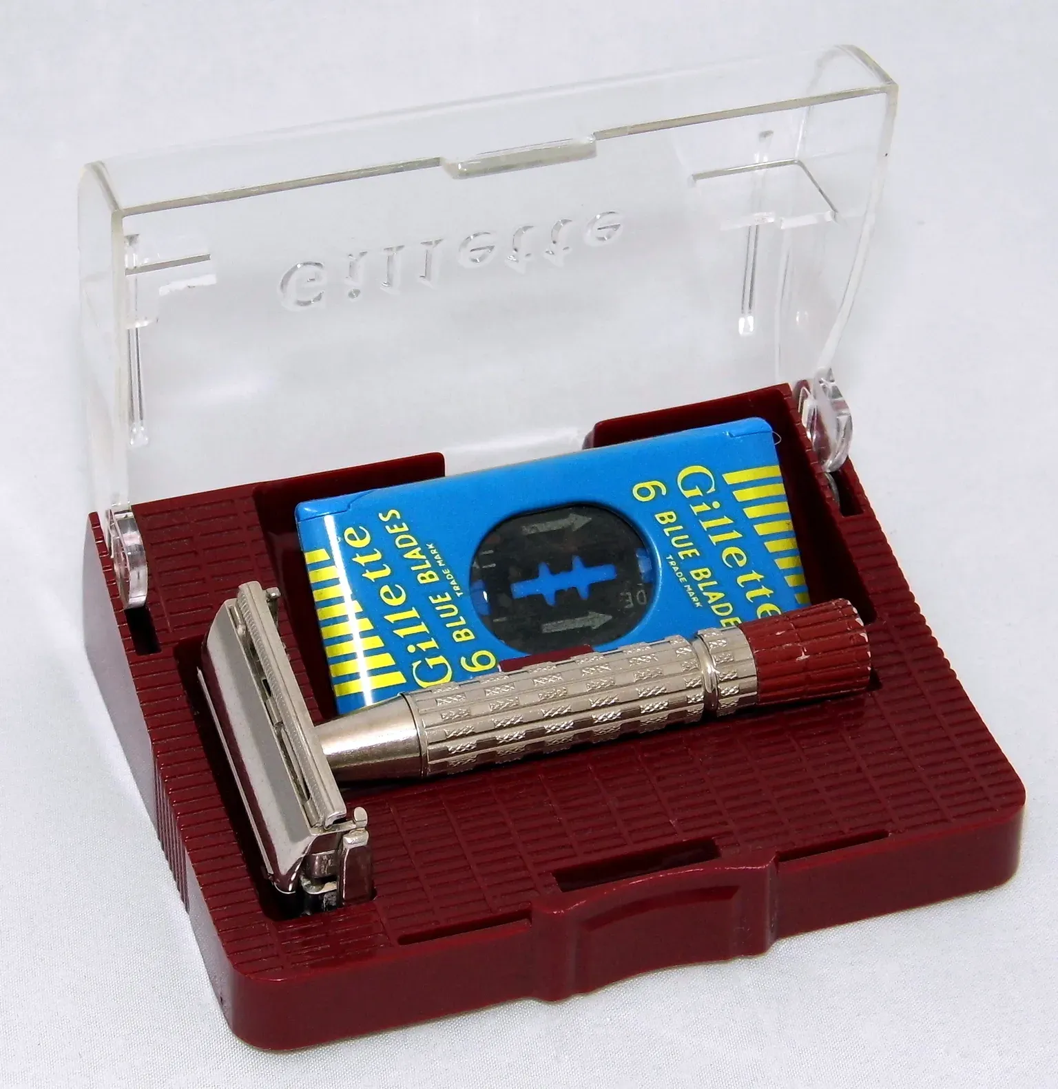 A Gillette Red Tip Super Speed twist to open razor resting in its red plastic case beside a pack of Gillette Blue Blades, a razor documented with the date code D-1 for the first quarter of 1958.